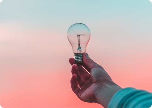 Hand holding a glowing lightbulb